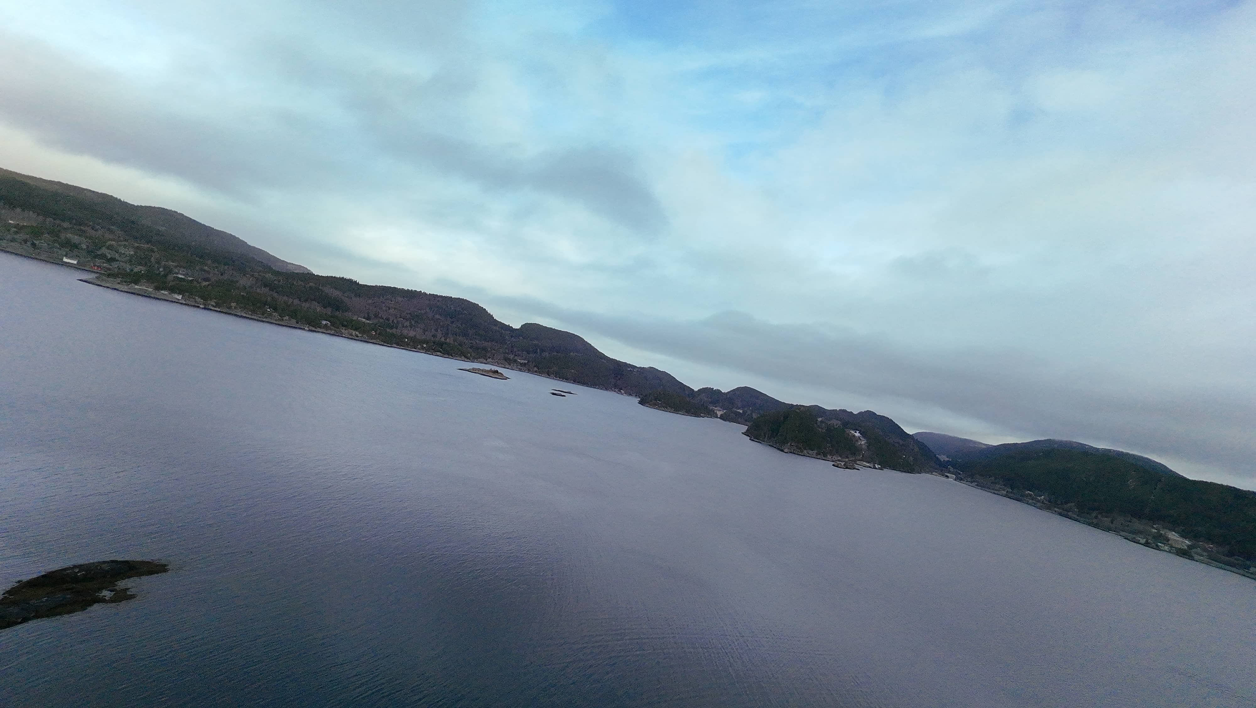 Dramatic aerial perspective of Langstein area showing the meeting of mountains and fjord waters, with distinctive Norwegian coastal landscape features